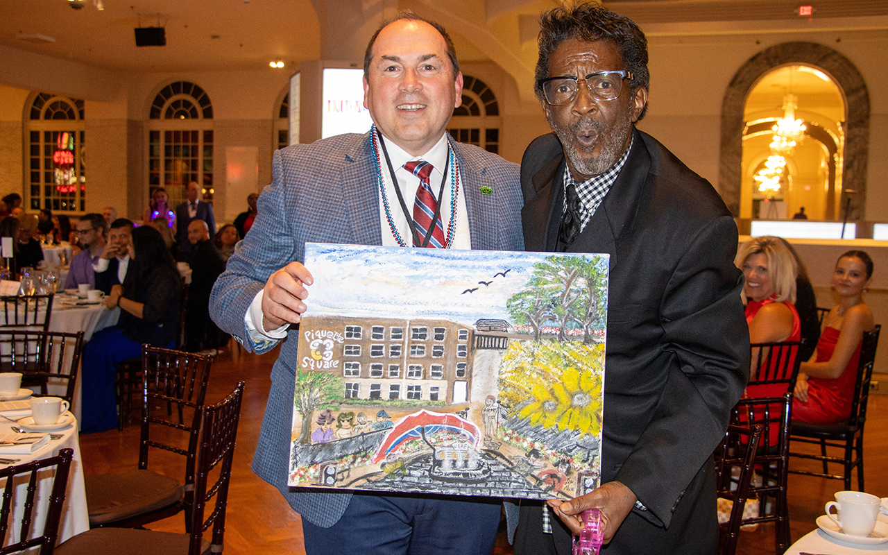 Two men holding a painting created for this auction