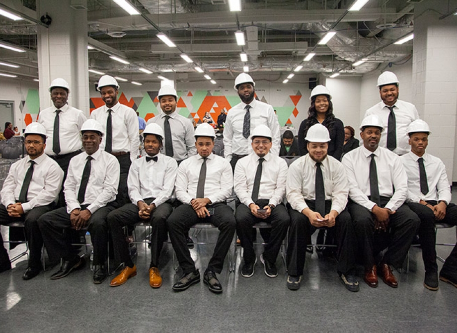 people in work attire line up for a photo within a large building