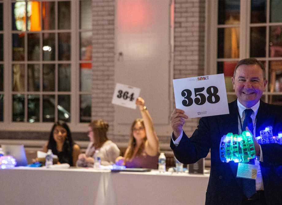 Man holding light up toys and a bidding number