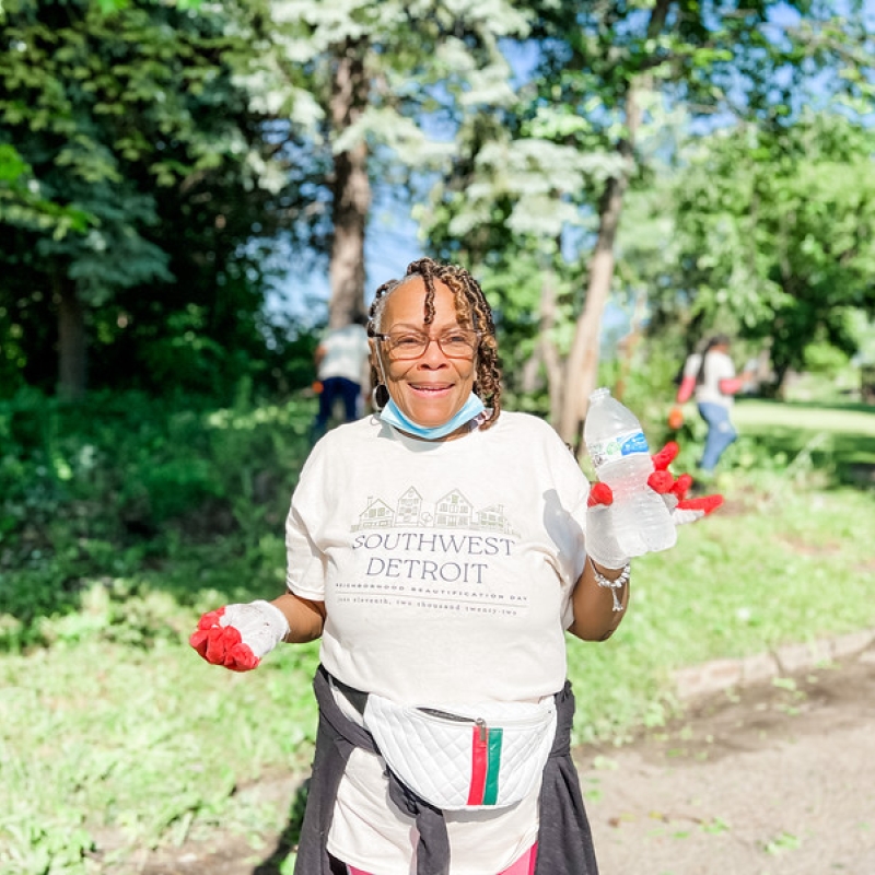 a woman walks in a park, smiling, and picking up trash