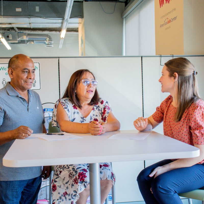 three people talking and sitting around a table