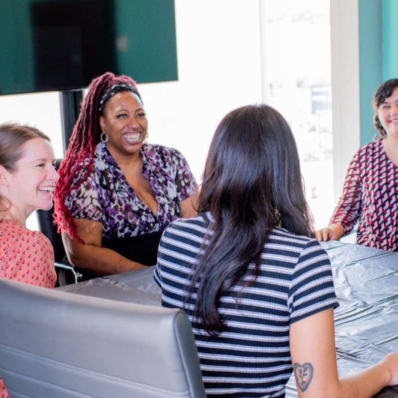 four people sitting around a table talking and smiling