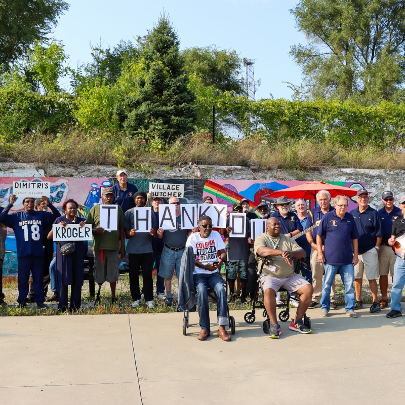 A large group of people stand together holding a sign that says "thank you"