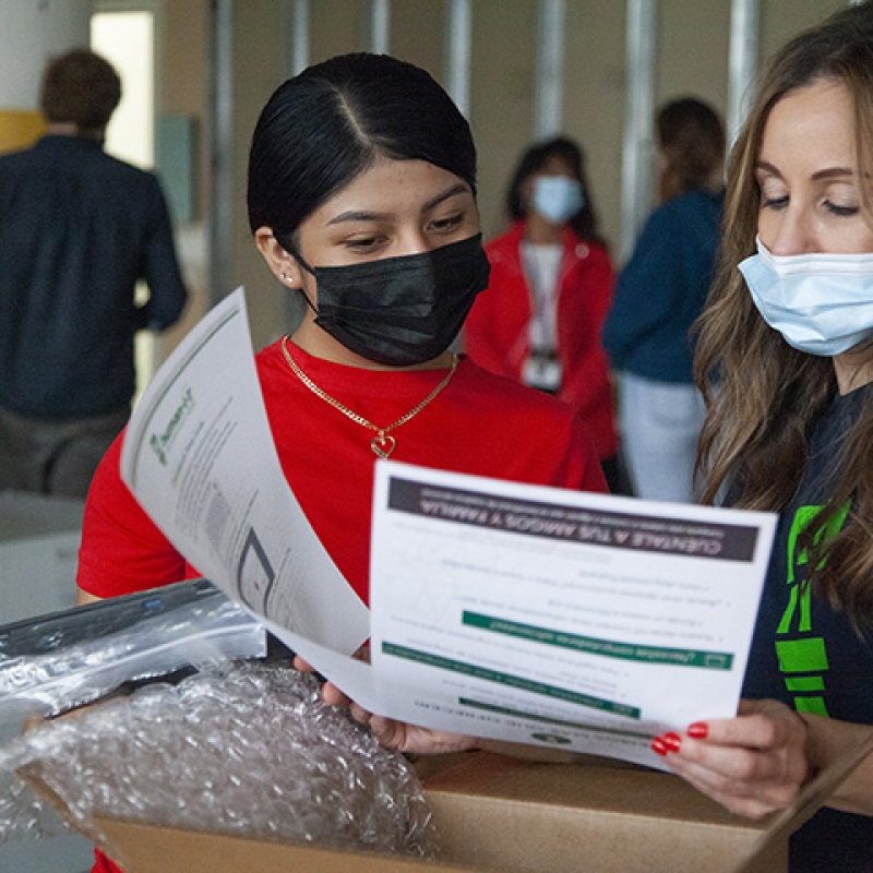 Rebeca Martinez receives a laptop from Jennifer Jambor, Project Manager with human-i-t, at the laptop giveaway event sponsored by Rocket Mortgage.