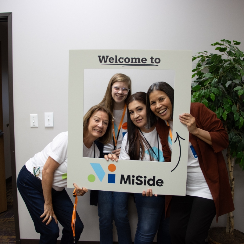 Four women standing behind the a frame that says "Welcome to MiSide"